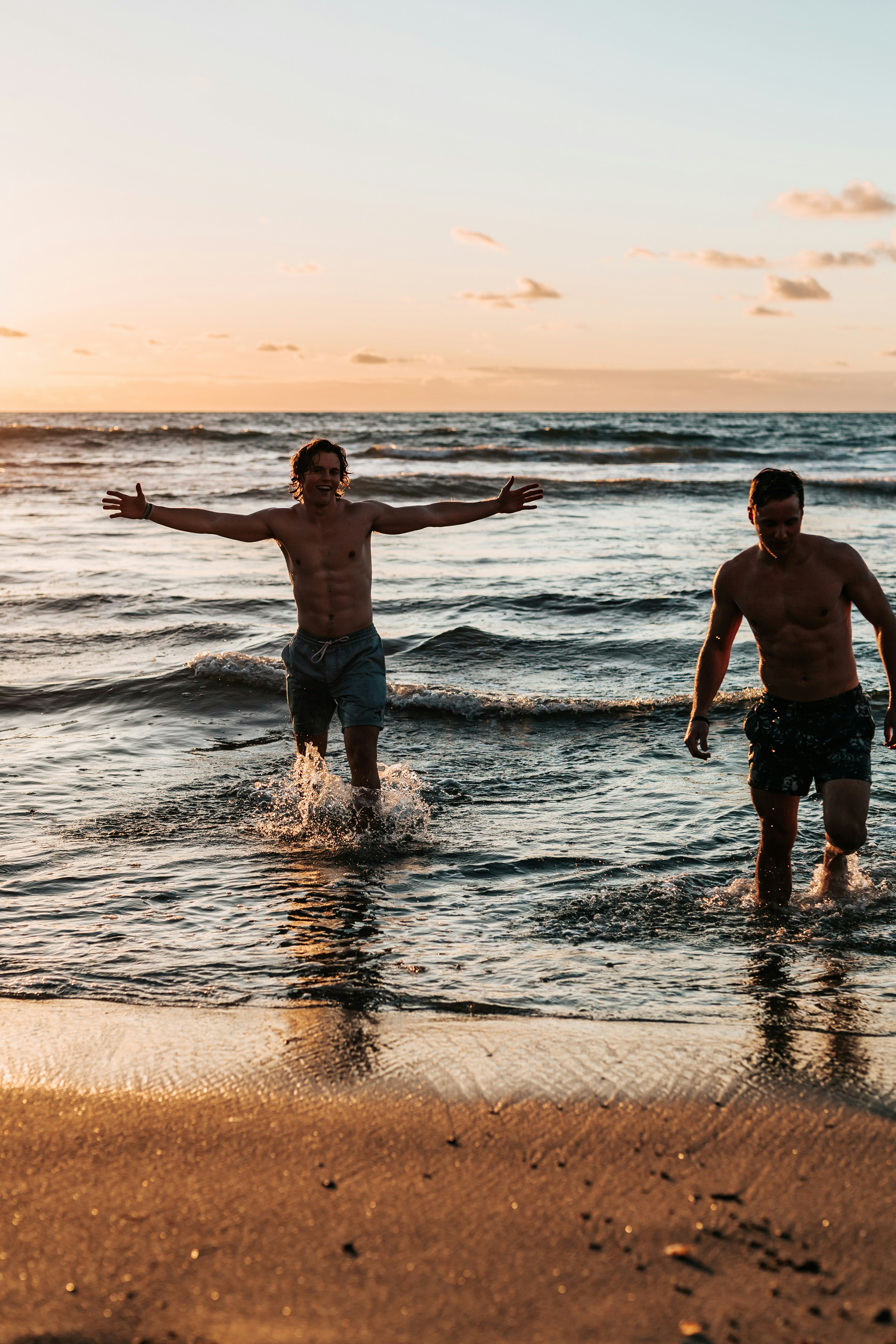 two men standing at shore during golden hour